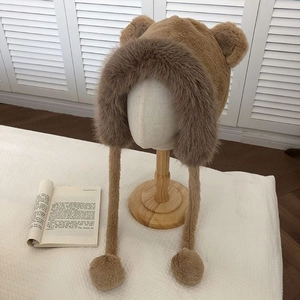 Detail of plush brown bear ear hat featuring soft faux fur and pom-pom ear flaps