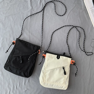 Detail of canvas crossbody bag with rope strap and vibrant orange side accent