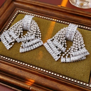 Close-up of luxury silver bow tassel earrings with sparkling rhinestones on green velvet