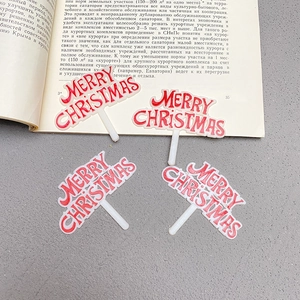 Macro shot of 4-piece Merry Christmas red and white cake toppers on dark background