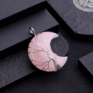 Detail of pink crystal moon pendant wrapped in silver wire tree of life pattern