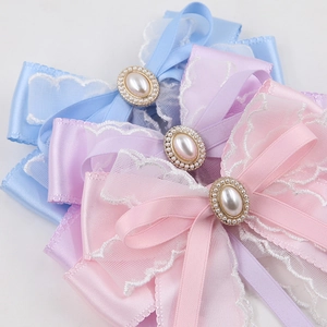 Detail of satin bow hair clips with pearls in pink, purple, and blue colors
