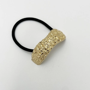 Close-up of golden textured metal hardware on a black elastic U-shaped hair tie