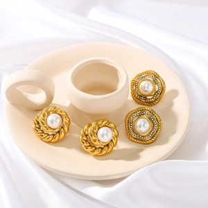 Set of gold stainless steel round earrings with pearls and rhinestones on silk background