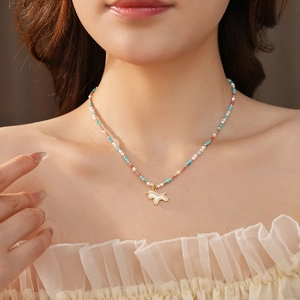 Detail of colorful beaded necklace with a golden unicorn pendant on a female model