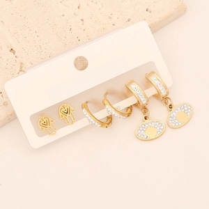 Close-up of golden earring set with Hamsa hand, evil eye and sparkling rhinestones