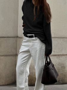 Women's casual black hooded knit sweater with white trousers and brown leather tote bag