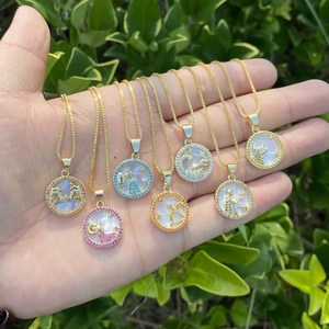 Detailed close-up of 18K gold zodiac pendants with colorful crystals and shell inlay