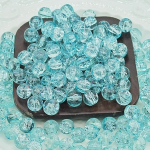 Macro shot of blue crackle glass round beads for DIY jewelry making on white tray