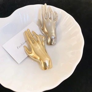 Macro shot of polished gold and silver palm pins on a white decorative porcelain plate