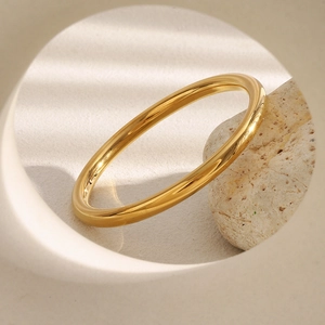 Gros plan détaillé d'un bracelet jonc évidé en acier inoxydable plaqué or 18 carats sur pierre