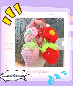 Detail of handmade crocheted strawberry keychain featuring small flowers and plastic clasp