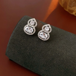 Macro shot of silver gourd stud earrings featuring pave-set cubic zirconia and oval diamonds