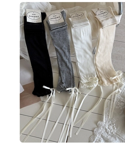 Close-up of ballet style ribbed leg warmers with ribbon bows in four colors