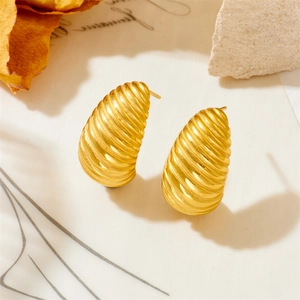 Macro detail of gold earrings featuring spiral texture and brushed metal finish