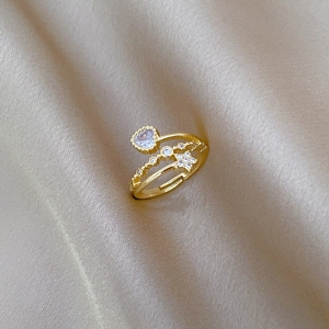 Detail of gold open ring with heart and star zircons on champagne silk background