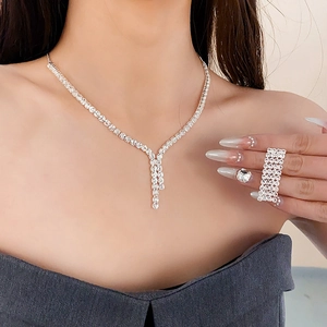 Detailed view of silver zircon tassel necklace and matching rhinestone rings on model