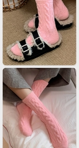 Close-up of pink cable knit thermal socks paired with fur-lined black double buckle sandals