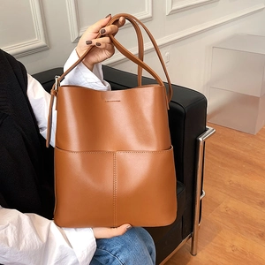 Braune Beuteltasche aus Leder mit Riemen, präsentiert von einem Model für modischen Look