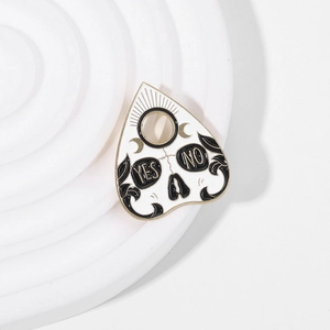 Detail of occult Ouija pointer enamel pin featuring skull, sun, moon, and yes no text