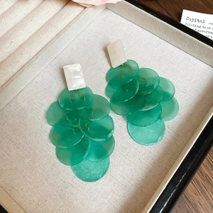 Detail view of long tassel earrings with green translucent discs and shell inlays