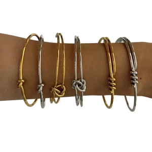 Knotted stainless steel bracelets in gold and silver finish shown on a wrist