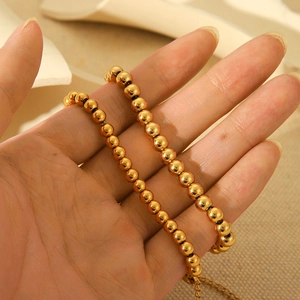 Minimalist 18K gold stainless steel bead chain bracelet held in hand with soft lighting