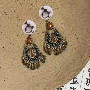 Détail de boucles d'oreilles vintage avec pierres ambrées et glands en perles