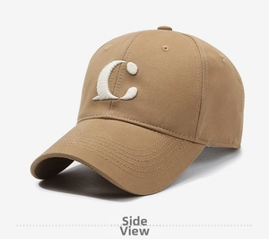 Detail of white 3D embroidered C letter on tan cotton twill baseball cap with curved brim