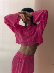 Close-up of pleated fabric texture on a rose pink flared sleeve crop top set