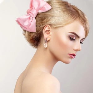 Pink satin bow hair claw clip and matching earrings shown on an elegant model profile