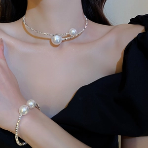 Detailed view of silver choker and bracelet featuring large faux pearls on a model