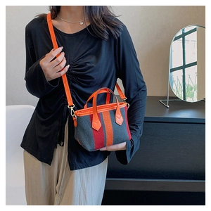 Model wearing a multi-color striped canvas crossbody bag with orange PU leather handles