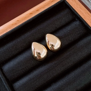 Close-up of polished gold teardrop earrings displayed in a black velvet jewelry box