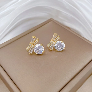 Detailed shot of golden butterfly earrings with white cubic zirconia on silk fabric