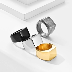 Detail shot of square signet rings in black, gold, silver, and vintage finishes on a pedestal