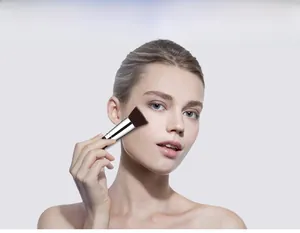Flat head foundation brush applied on model face with black handle and silver ferrule