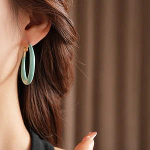 Vue latérale d'un mannequin portant des créoles rondes en résine turquoise et or