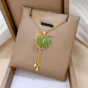 Detailed close-up of gold butterfly necklace with green stones and elegant tassels
