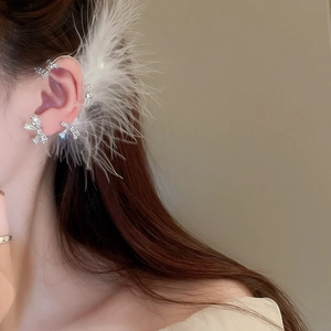 Macro shot of silver bow ear cuff featuring sparkling rhinestones and soft white feathers