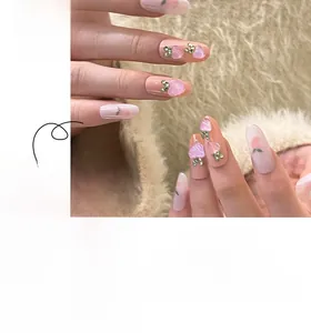 Detail of pink peach press-on nails with 3D heart gems and green leaf patterns