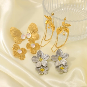 Elegante set di orecchini a fiore e farfalla in oro e argento su sfondo di seta beige