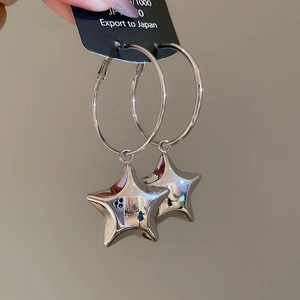 Dettaglio ravvicinato di un orecchino a cerchio argento con ciondolo a stella lucida
