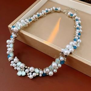 Dettaglio di collana vintage con perle e perline blu su vassoio beige e luce soffusa
