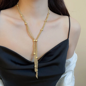 Detail of a multi-layered gold Y-necklace with small metal beads on a model