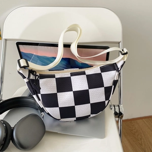 Checkerboard pattern crescent waist bag for men and women on white chair with gadgets