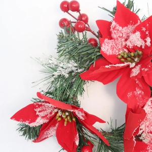 Detailed close-up of faux poinsettia flower with pine needles and artificial snow powder