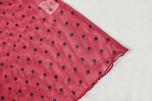 Close-up of red and black polka dot mesh fabric with size S label on a slim dress