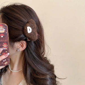 Close-up of a model wearing a brown plush bear hair clip on the side of her hair
