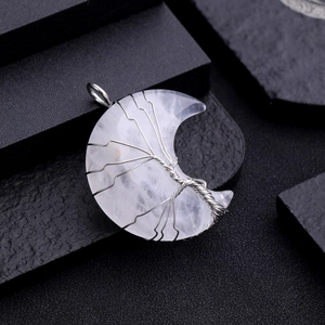 Macro shot of quartz moon pendant with silver wire-wrapped tree of life design